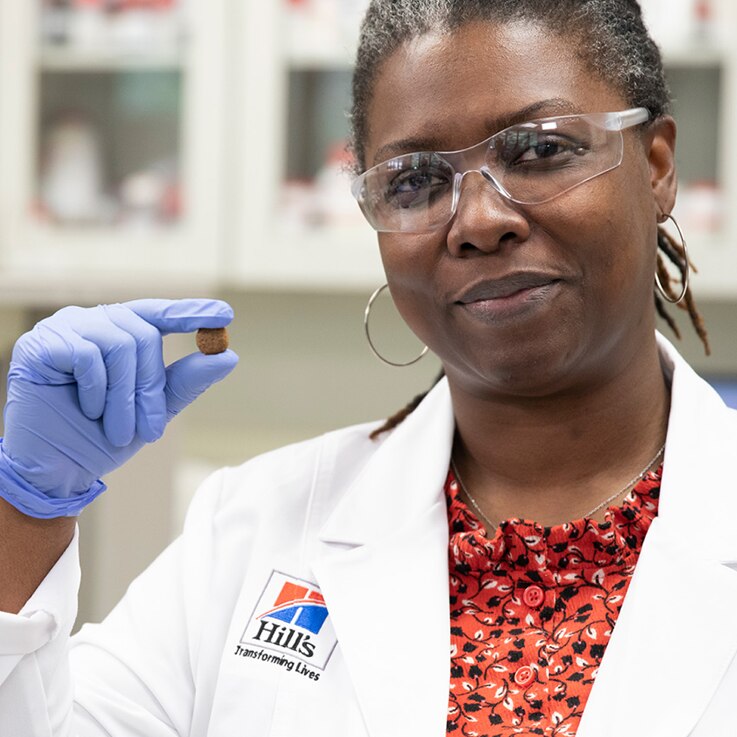 Hill's research scientist holding one piece of kibble